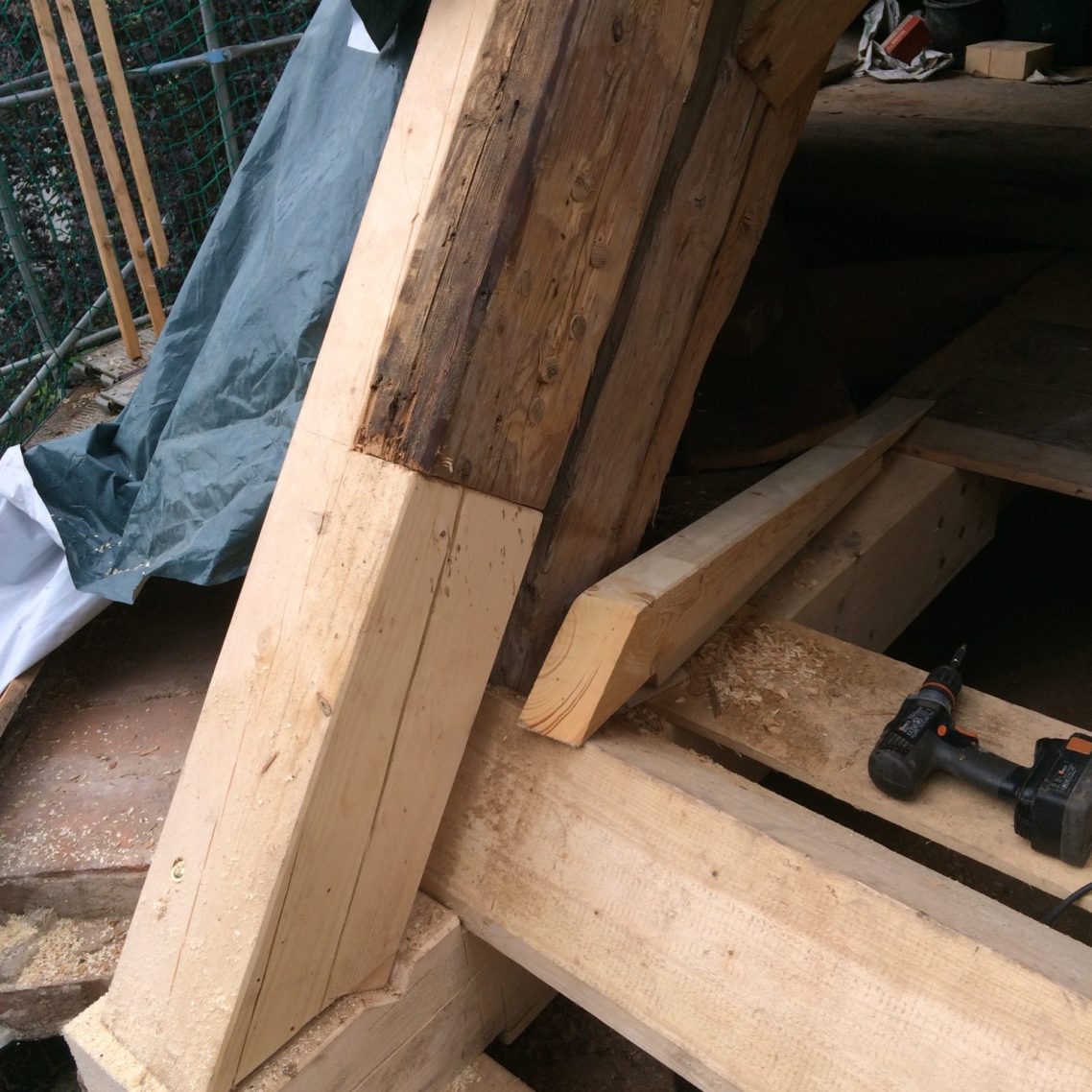 Saniertes Holz-Dachtragwerk mit neu eingesetzten Balken neben historischem Bestandsholz